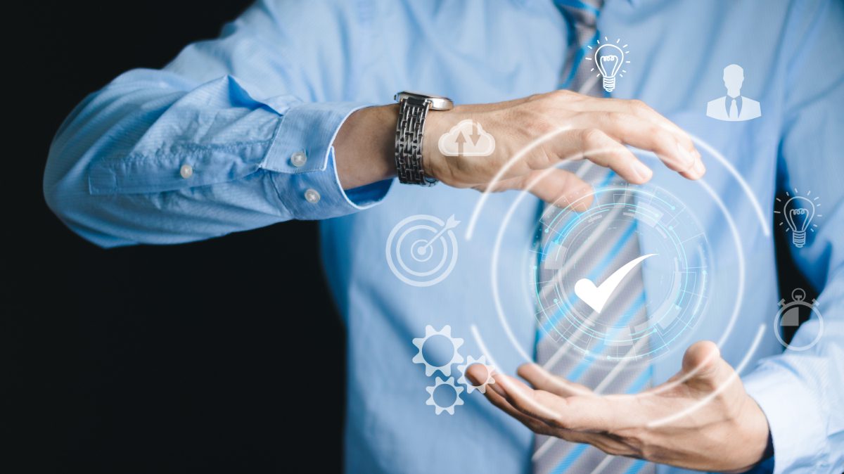 it-compliance-image-with-graphics-between-two-hands Image of cyber-graphics between two hands with a checkmark in the middle.