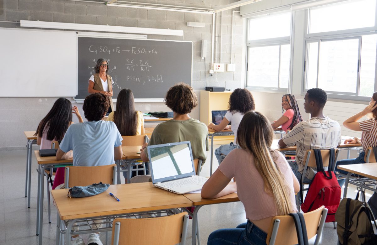 Female teacher explaining science to a class of diverse teenage students to help illustrate Education IT Services