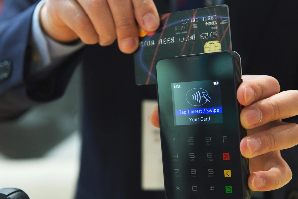 Guest tapping a credit card on a contactless payment terminal protected by PCI-focused security
