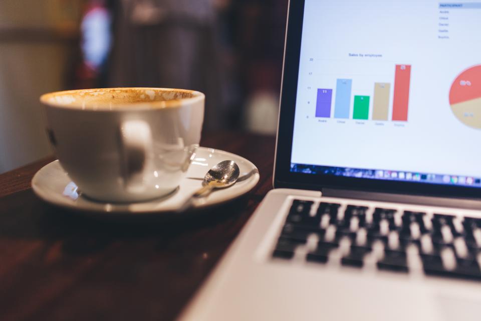 Coffee next to a laptop showing charts, representing a technology roadmap for hospitality businesses